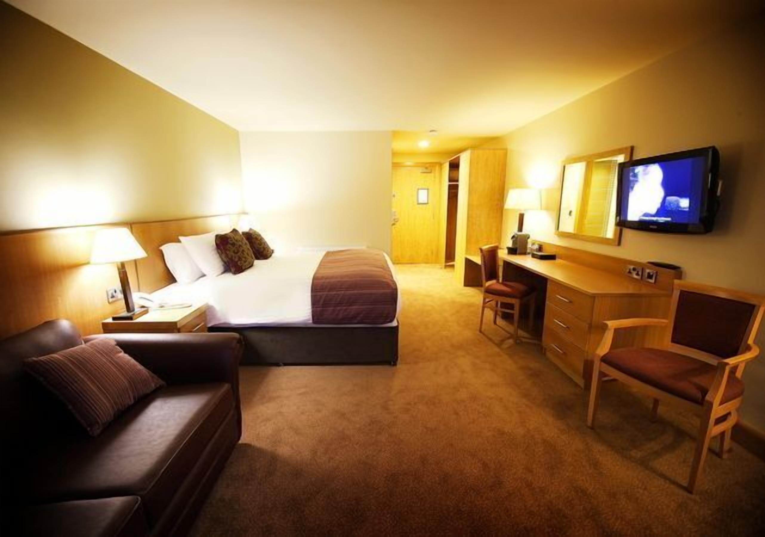 Une chambre d’hôtel équipée d’un lit, d’un bureau, d’une chaise et d’un téléviseur.