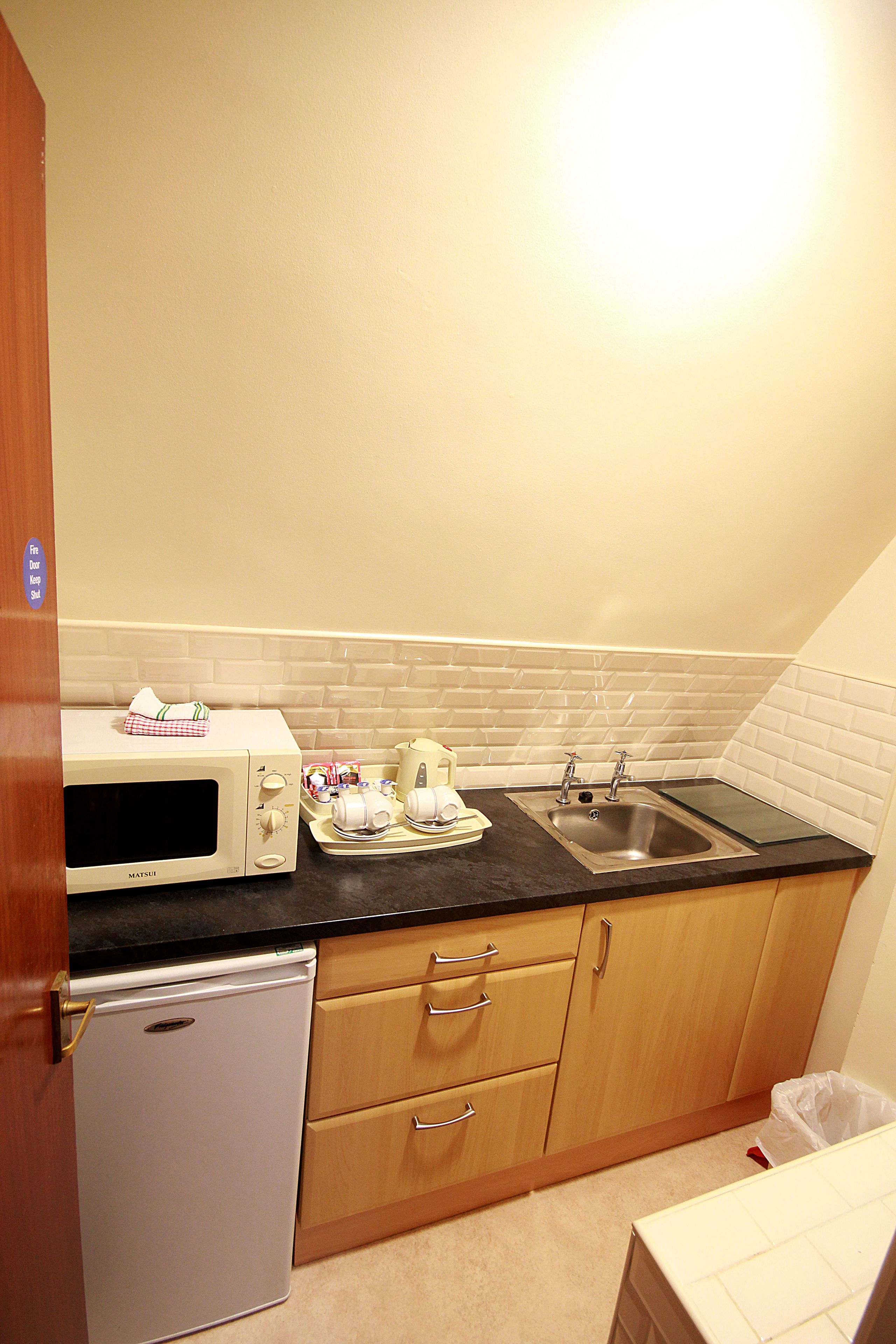 A compact kitchenette with a microwave, toaster, sink, and a small refrigerator.