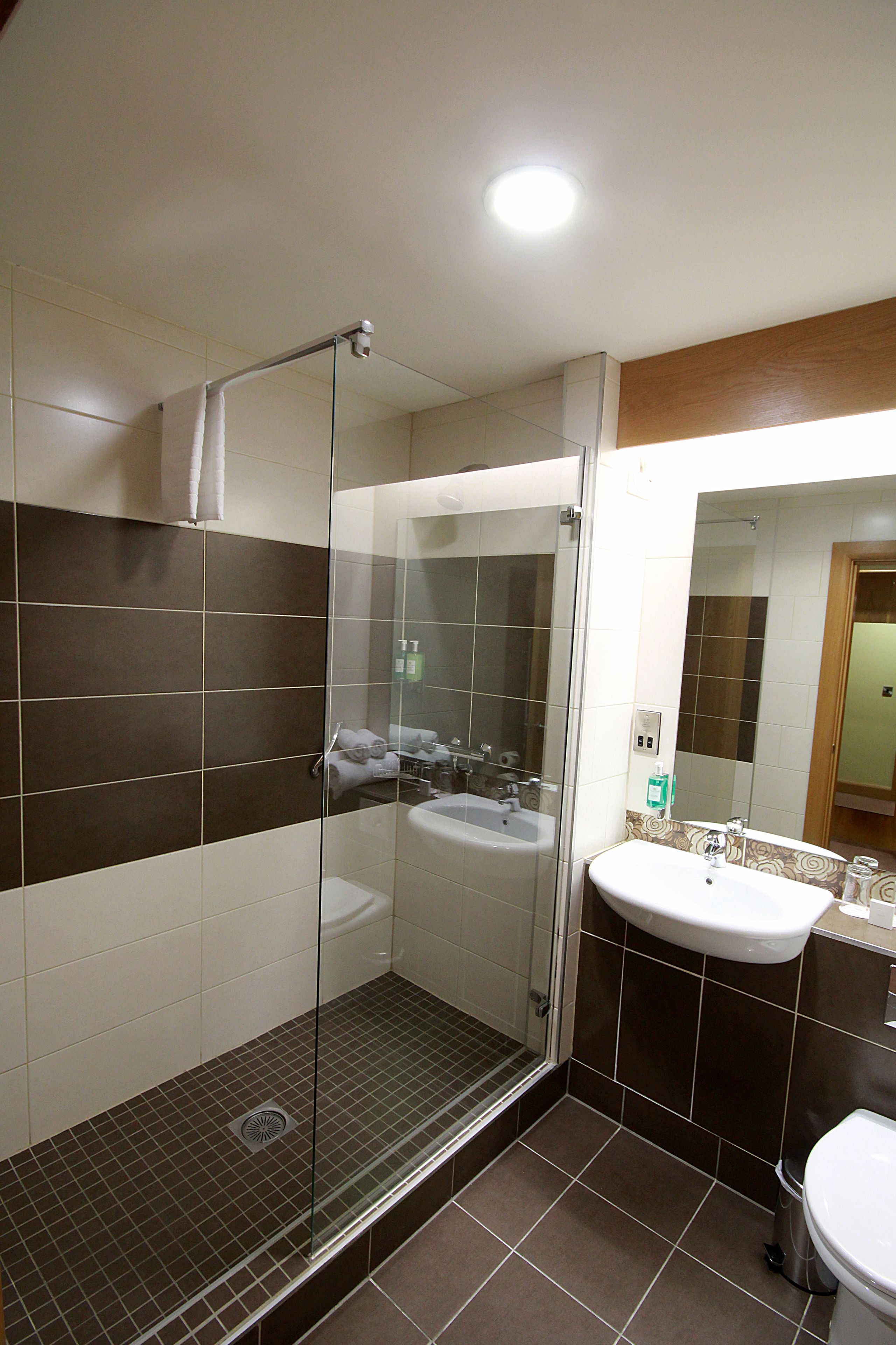 A modern bathroom with a glass-enclosed shower, a sink, and a mirror.