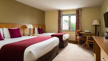 A hotel room with two beds, a desk, a chair, and a television.