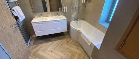 Une salle de bain moderne avec un meuble-lavabo à deux vasques, une baignoire sur pieds et une douche à l’italienne.