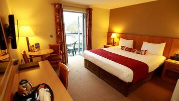 A hotel room with a bed, a desk, a chair, a table, a TV, and a balcony with a chair.
