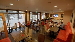 A restaurant with multiple tables and booths, large windows, and a television screen on the wall. - Belmore Court & Motel (Enniskillen)