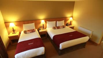 A hotel room with two beds, each with a red blanket, white linens, and bedside lamps.