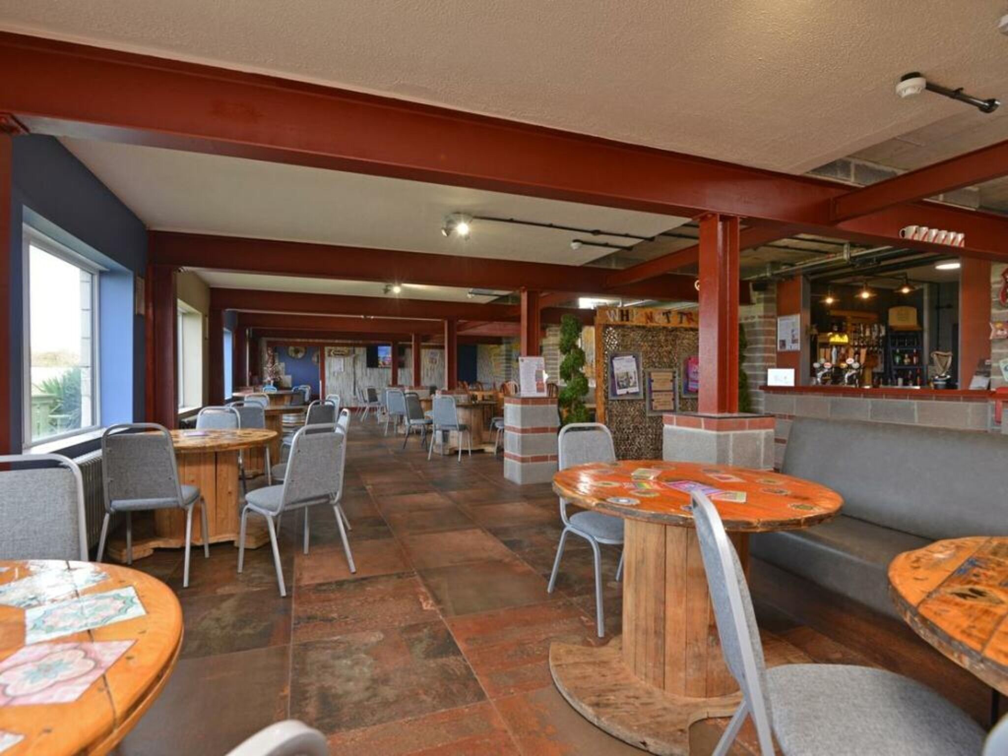 Un restaurant doté de nombreuses tables et chaises, d’un bar et d’un comptoir où est affiché le menu.
