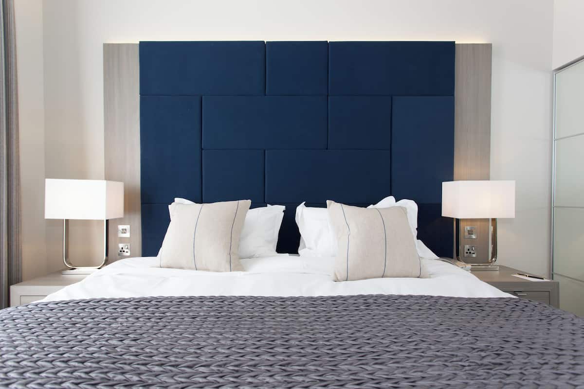 Une chambre d’hôtel moderne avec un grand lit, deux lampes de chevet et une tête de lit sombre.