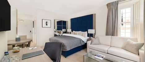 A hotel room with a bed, a sofa, a desk, and a glass coffee table.