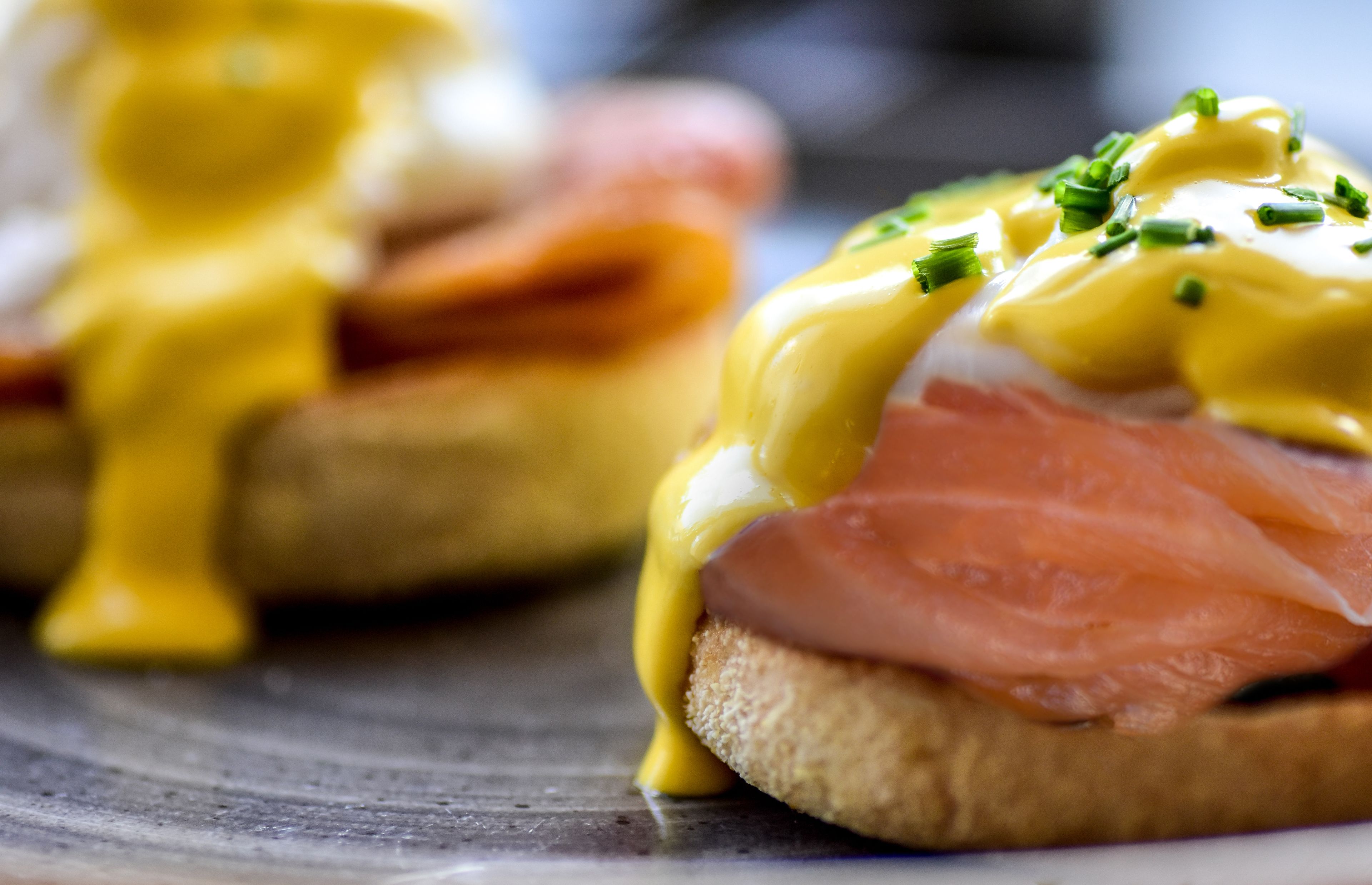 A close-up of a breakfast dish with eggs, smoked salmon, and hollandaise sauce.