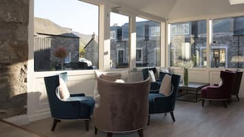 Un salon spacieux doté de grandes fenêtres, de murs en pierre et de meubles modernes.