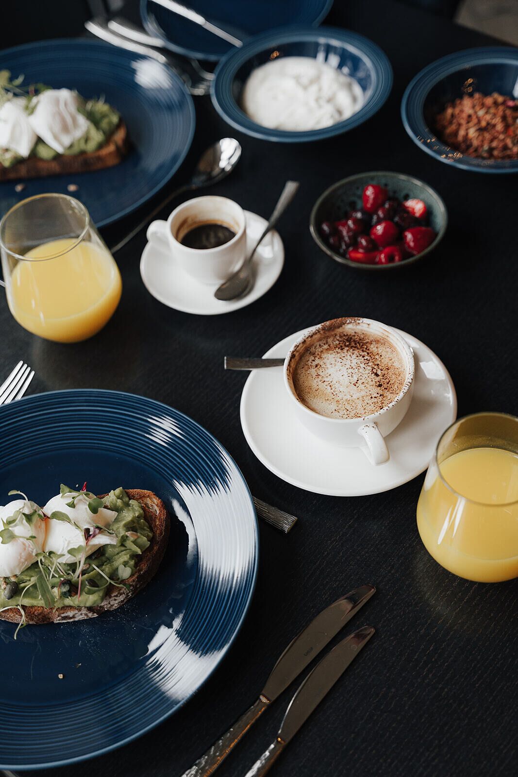 A breakfast setting with toast, coffee, and fruit on a table.