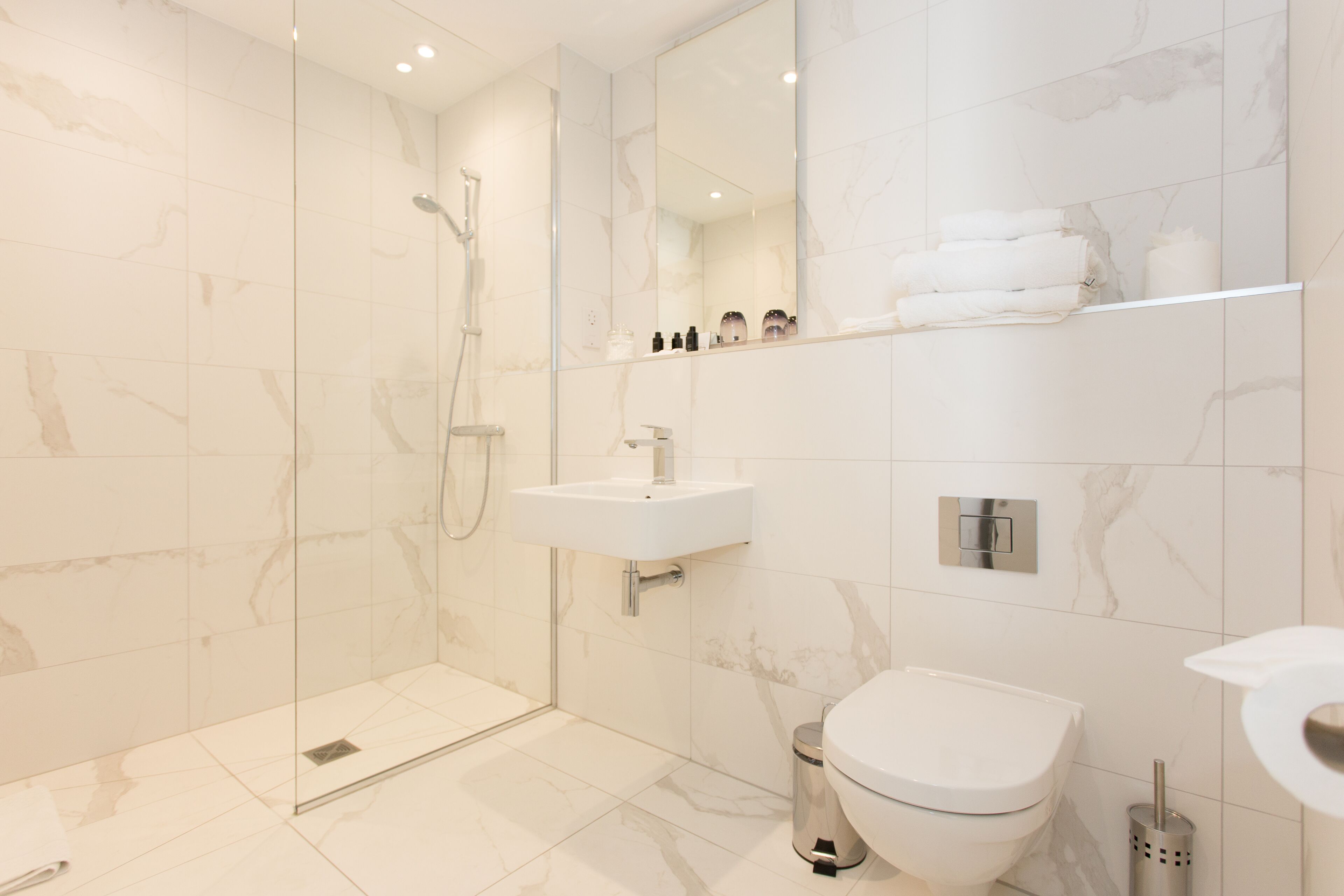 Ein modernes Badezimmer mit einer Duschkabine, einem weißen Waschbecken und einer Toilette.