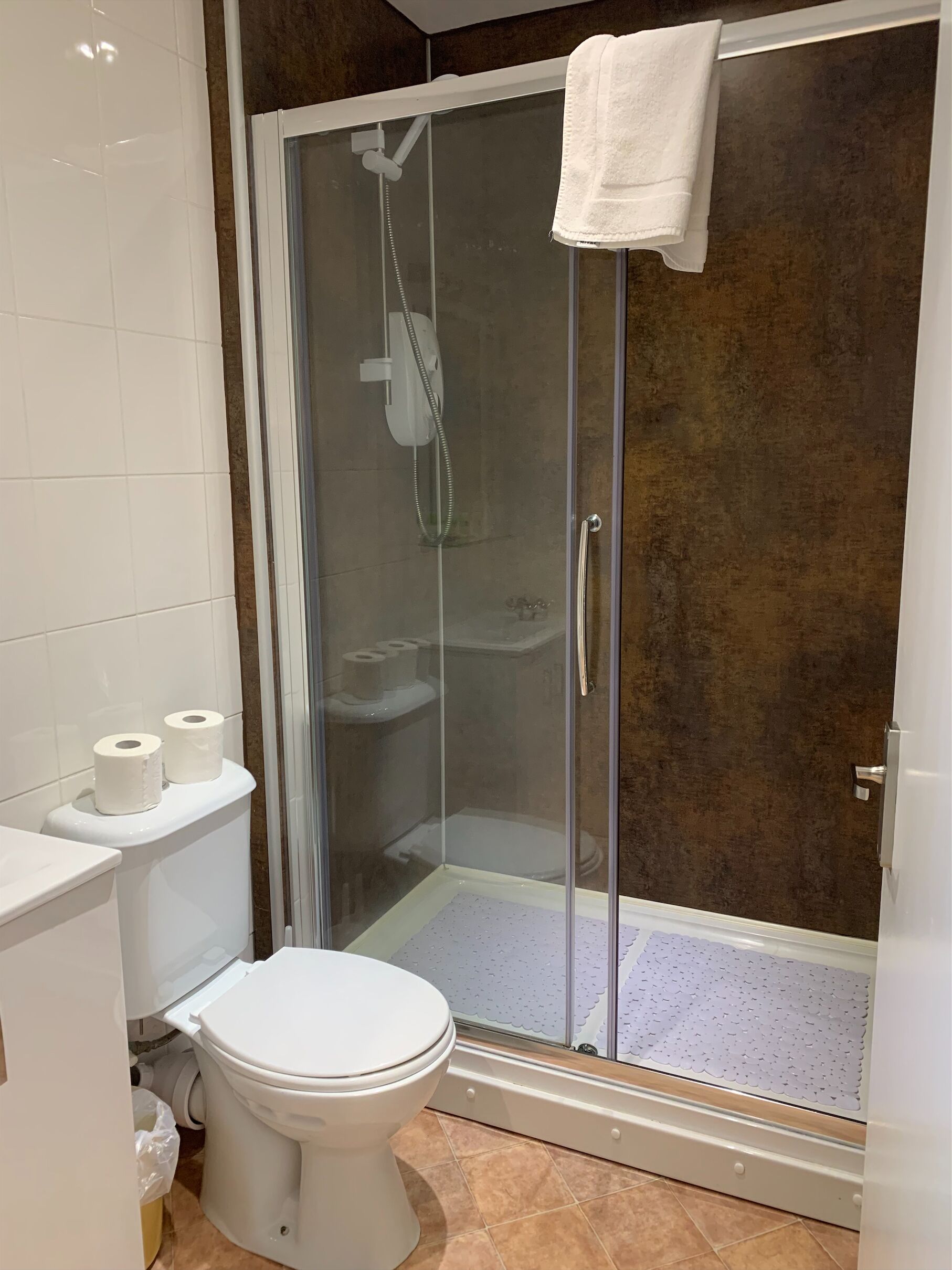 Un baño moderno con ducha de vidrio, inodoro y lavamanos.