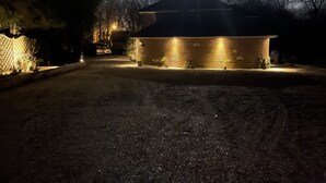 Un edificio con fachada de ladrillo, rodeado por un camino de grava y una valla de madera.