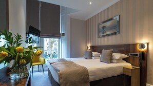 Une chambre d’hôtel moderne, dotée d’un grand lit, d’une table de chevet et d’une chaise.