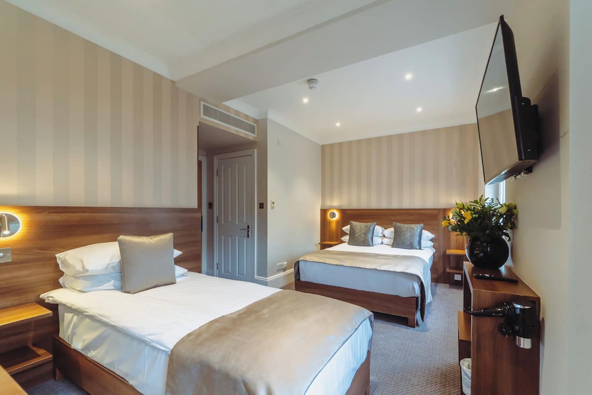 A hotel room with two beds, a TV mounted on the wall, and a coffee machine.