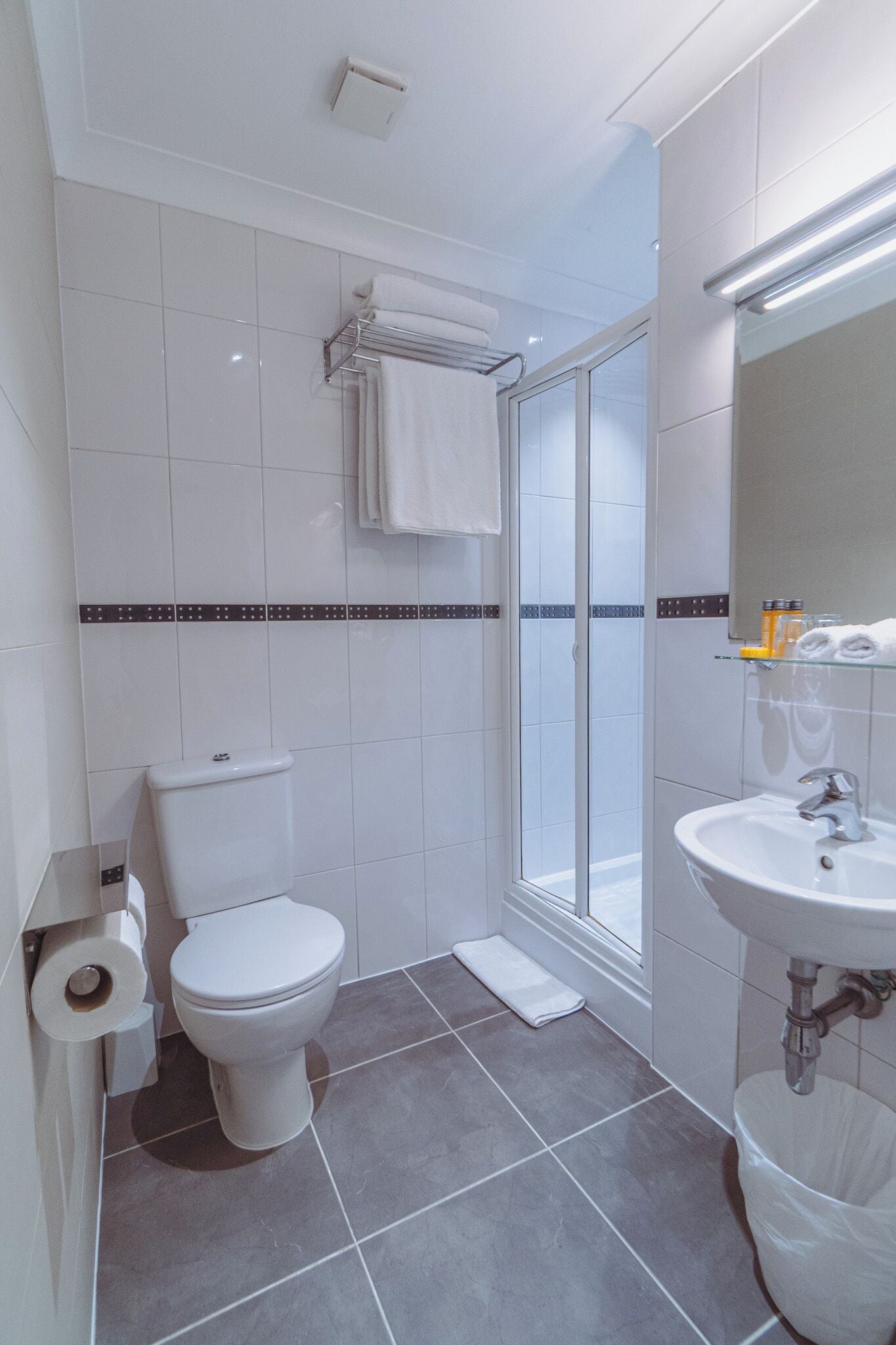 A modern bathroom with a toilet, shower, and sink.