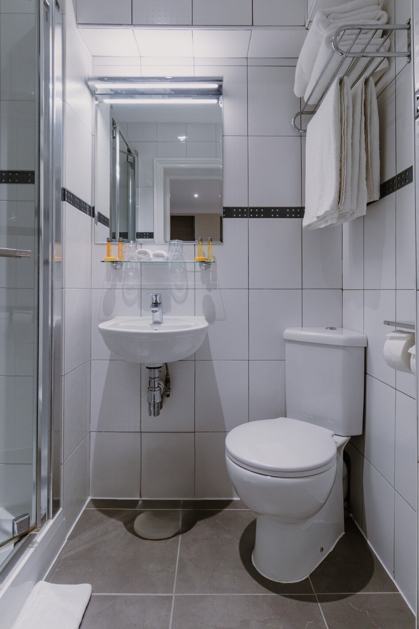 Un baño moderno con cabina de ducha de vidrio, un lavamanos blanco y un inodoro.