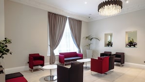 Un salon moderne avec des fauteuils rouges et noirs, un canapé et un lustre.