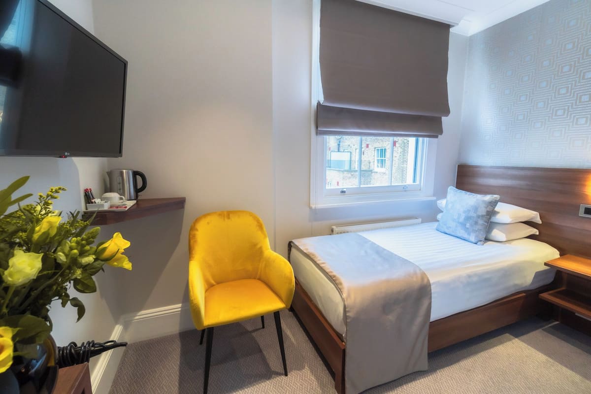 A hotel room with a bed, a chair, a TV, a window with a view, and a bedside table.