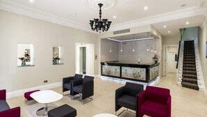 Un vaste espace de vie aménagé avec des meubles modernes, une table blanche au centre et un escalier menant à un niveau supérieur.
