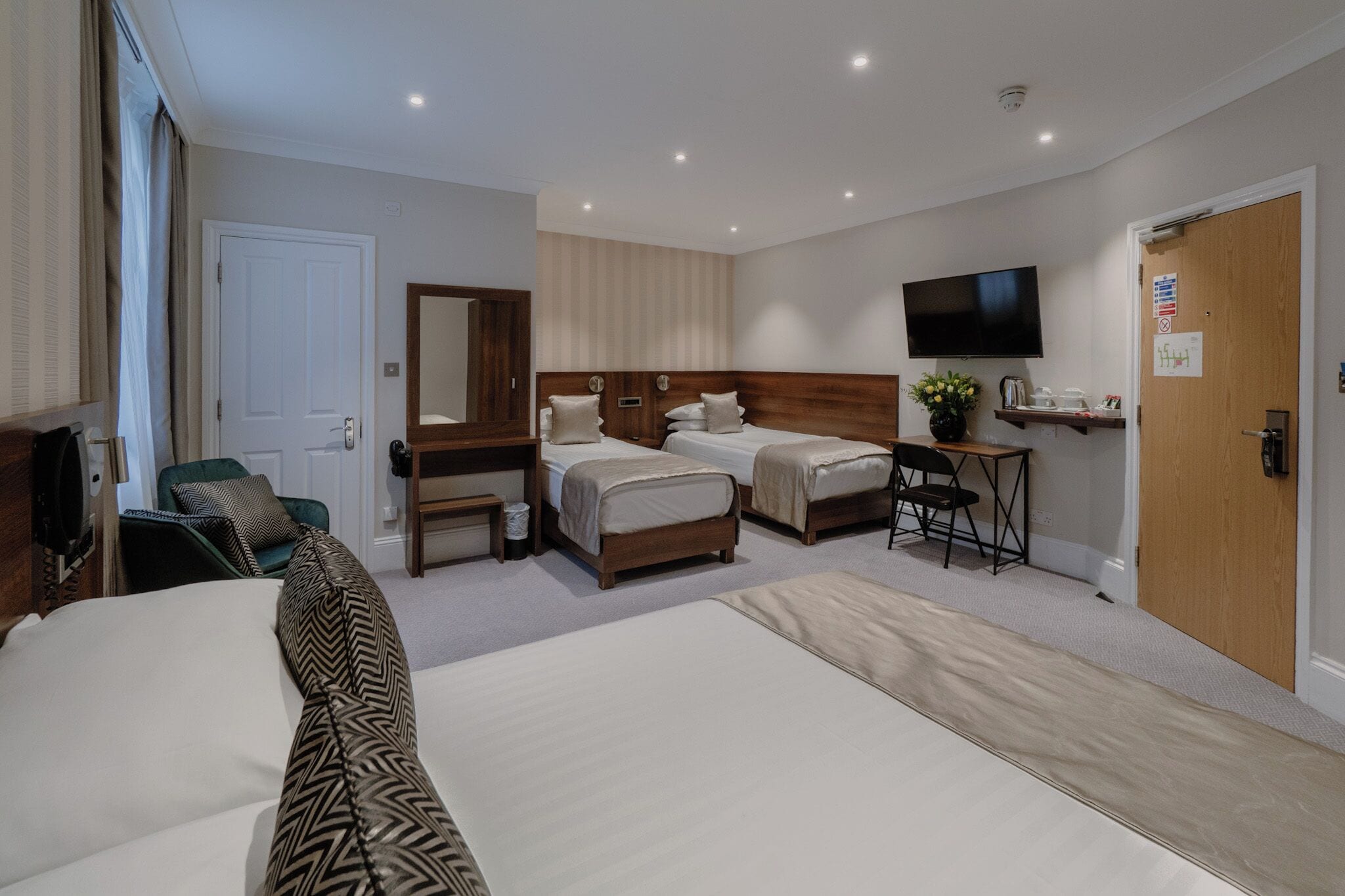 A hotel room with two beds, a TV, a desk, and a chair.