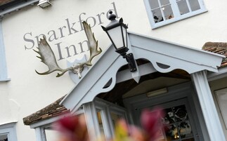 Un edificio con un letrero que dice "Sparkford Inn" y una cabeza de alce decorativa sobre la entrada.