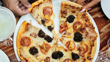 Eine Pizza mit verschiedenen Belägen, ein Glas Weißwein und ein Löffel auf einem Tisch.