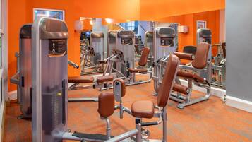 A gym with orange walls and various exercise machines.