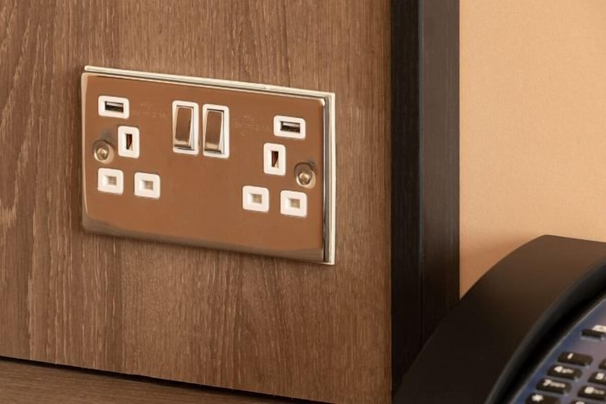 Une prise électrique murale dotée de plusieurs prises et d’un téléphone, le tout posé sur une surface en bois.
