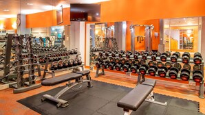 Un gimnasio con equipo de levantamiento de pesas, bancos y una variedad de mancuernas.