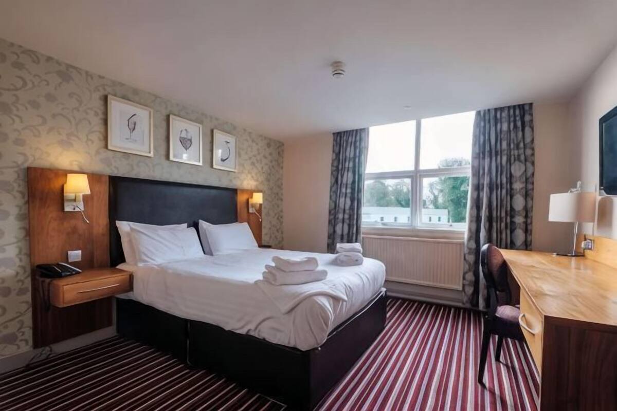 Une chambre d’hôtel avec un grand lit, des lampes de chevet, un bureau et une vue sur l’extérieur.