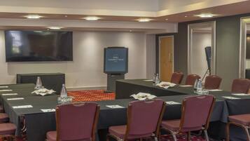 Un salón de conferencias con una gran mesa, sillas, un televisor de pantalla plana y un cartel que dice "HULL HUMBERT VIEW HOTEL".