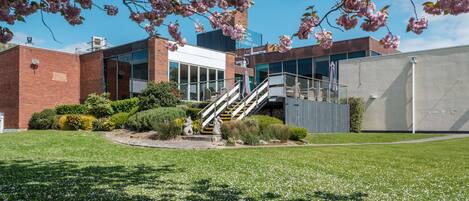 A building with a brick facade, a glass entrance, and a staircase leading to a second floor.