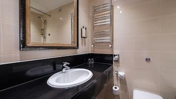 A modern bathroom with a black sink, a mirror, a towel rack, and a toilet.