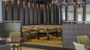 A modern lounge area with leather sofas, a coffee table, and a bar area with a minibar. - Hull Humber View Hotel, Sure Hotel Collection by BW (North Ferriby)