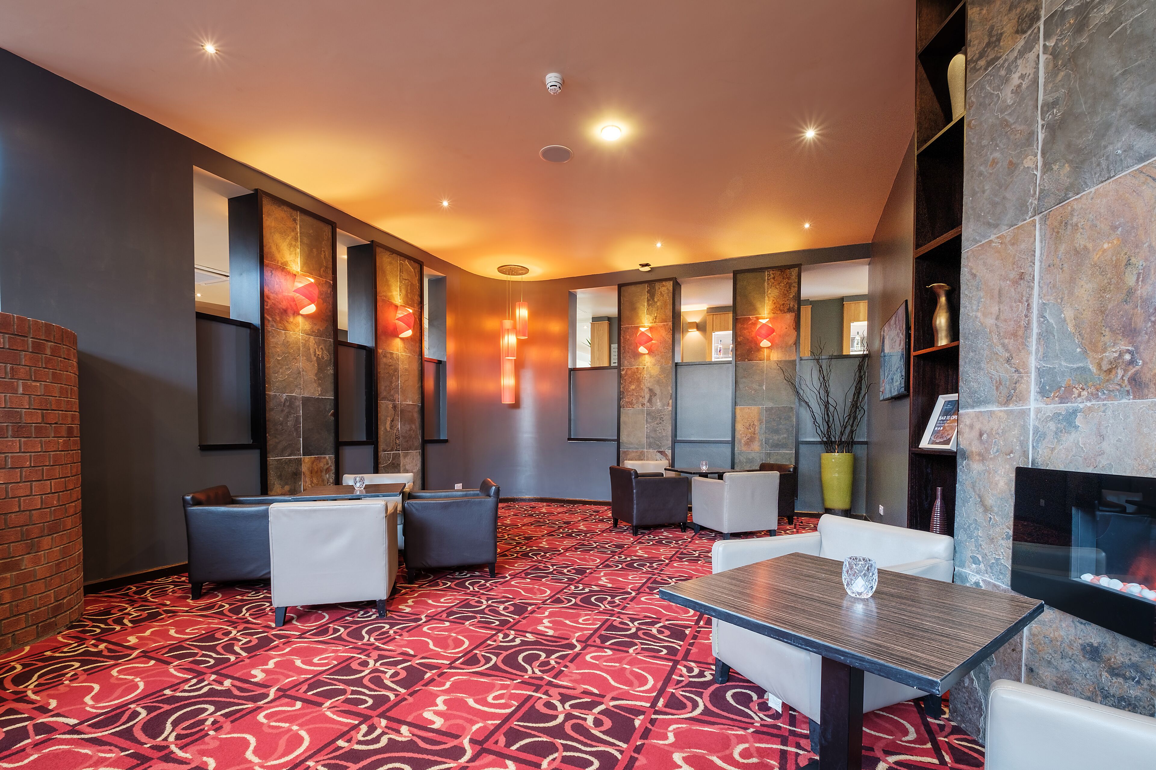 A modern lounge area with seating arrangements, a fireplace, and decorative wall panels.