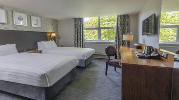 Habitación de hotel con dos camas, un escritorio, una silla y una ventana con cortinas.