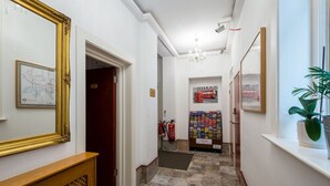 A hallway with a wooden bench, a map on the wall, a fire extinguisher, and a vending machine. - Adria Hotel (London)