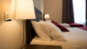 A hotel room with a bed, a bedside lamp, and a window with curtains. - Adria Hotel (London)