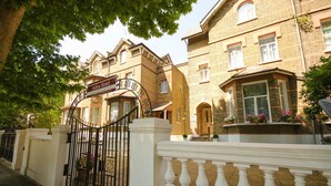 A traditional brick building with a gated entrance, a sign reading "Adria Hotel," and a white balustrade. - Adria Hotel (London)