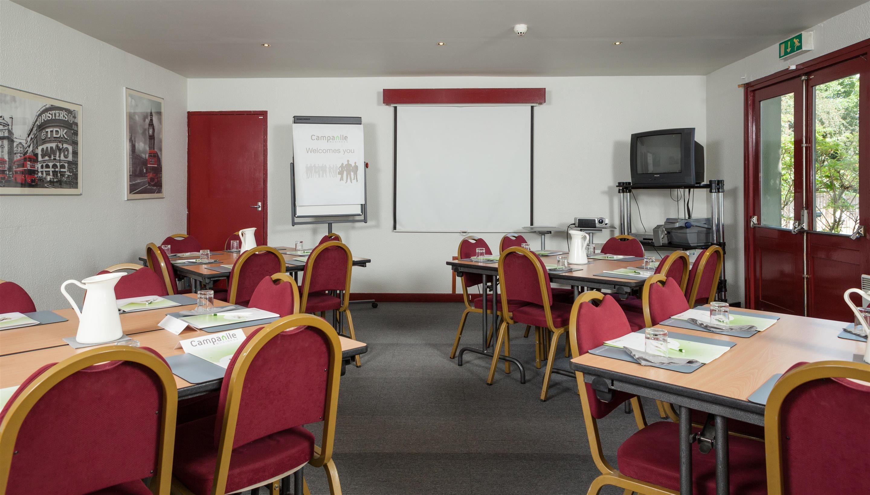 A conference room with red chairs, a whiteboard, and a projector.