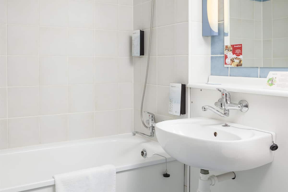 A modern bathroom with a white bathtub, a white sink, and a mirror above the sink.