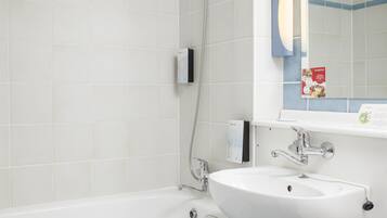 Une salle de bain moderne avec une baignoire blanche, un lavabo blanc et un miroir au-dessus du lavabo.