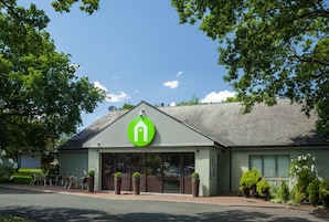 A building with a green logo, large windows, and outdoor seating.