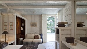 A cozy room with a bed, a sofa, a small table, and a shelf with decorative items.