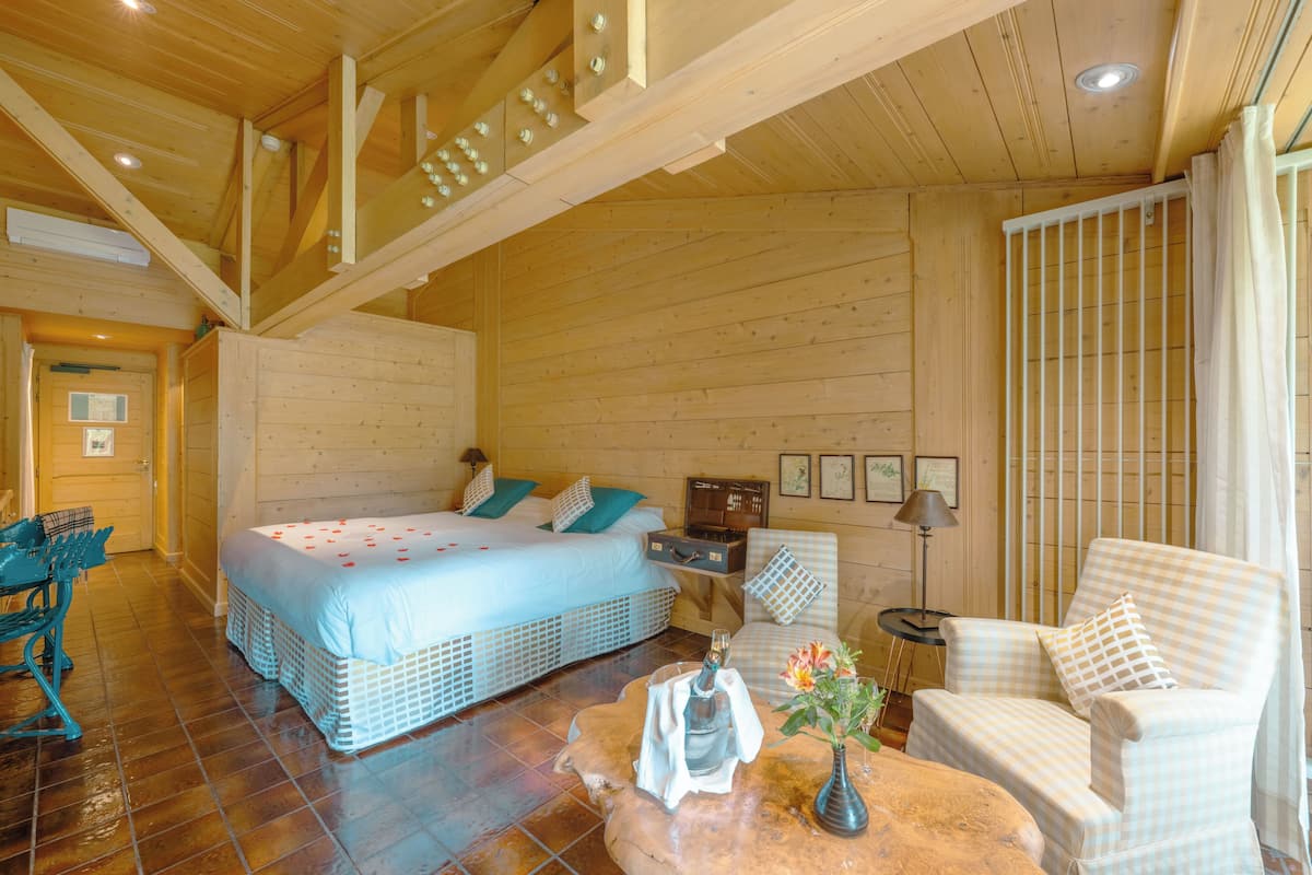 Ein Holzblockhaus-Interieur mit einem Bett, einem Sessel, einem Tisch und einem Schreibtisch.