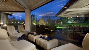 A modern outdoor seating area with leather sofas and tables, a pool, and a view of the surrounding landscape.