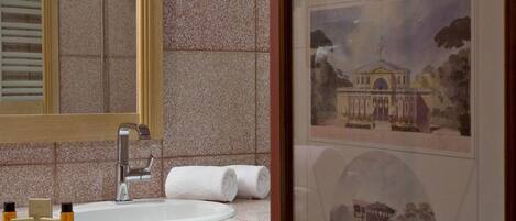 A bathroom with a large mirror, a sink, and a framed architectural drawing on the wall.
