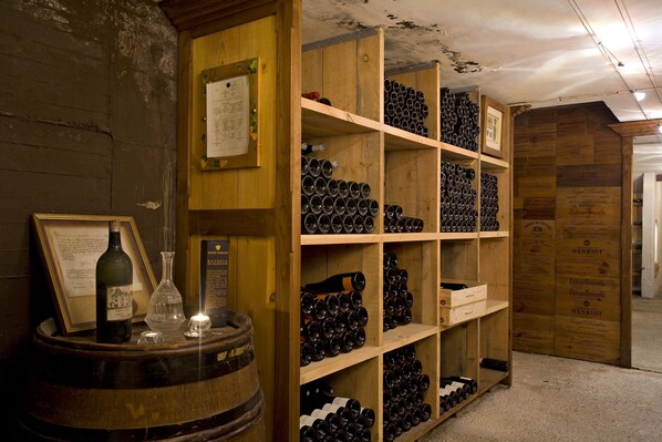 Une cave à vin avec des étagères en bois remplies de bouteilles de vin et une barrique en bois.