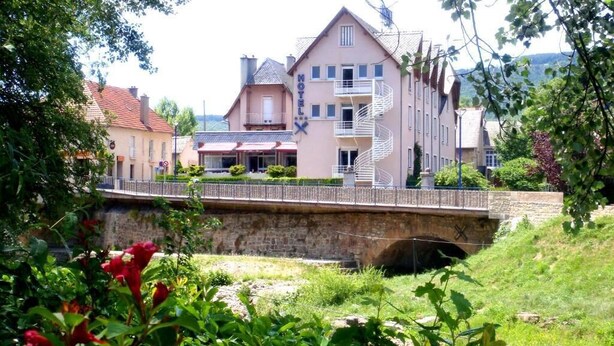 Ein Hotel mit einer markanten Treppe, einer Steinbrücke und üppiger Bepflanzung.